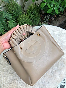 young woman left hand hold beige leather fashionable hand bag for working