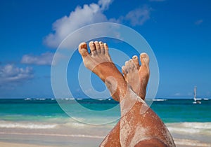 Young woman legs sunbathing on the beach