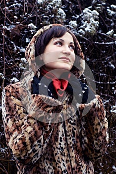 Young woman in leopard fur coat looking up
