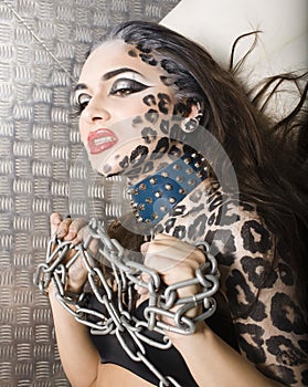 Young woman with leopard make up all over body, cat bodyart closeup in chains