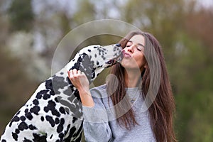 Young woman licked in the face by an Dalmatian dog