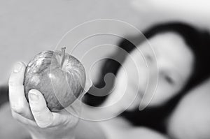 Young woman lies in bed and holds an apple