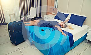 Young woman lies and has a rest on the bed in the hotel room.