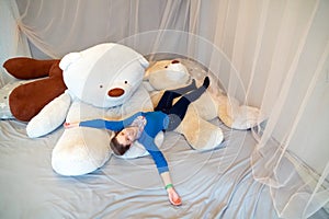 A young woman lies on huge soft bears