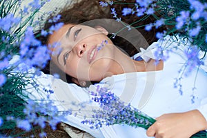 Young woman lies in the lavender flower field, beautiful summer landscape