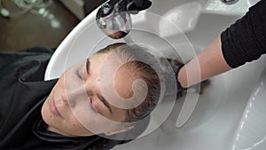 young woman, lies in a salon, washes her hair in a hairdressing salon by a stylist. Handsome client relaxing while