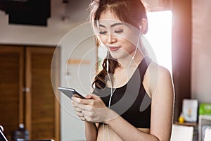 Young woman lifestyle running treadmill using smart mobile phone