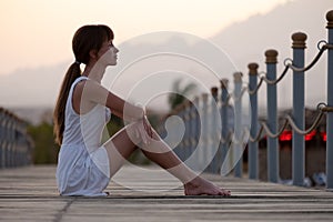 Young woman in light dress enjoying warm sunny evening on sea shore. Summer vacations and travelling concept