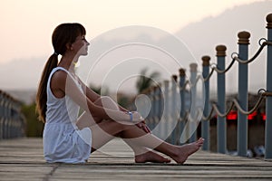 Young woman in light dress relaxing on warm sunny morning on sea shore. Summer vacation and travelling concept