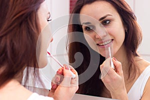 Young woman lip glossing in bathroom