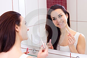 Young woman lip glossing in bathroom photo