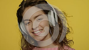 Young woman listen music in headphones. Happy girl in headphone on yellow