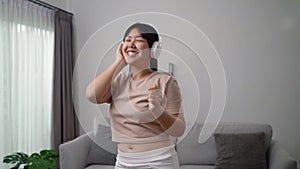 Young woman listen to music with headphone and dance in the living room at home.