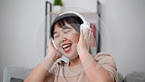 Young woman listen to music with headphone and dance in the living room at home