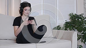 Young woman listen to music sitting on sofa at home 4K