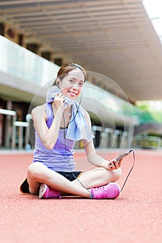 Young Woman listen to music and sitting on sport stadium