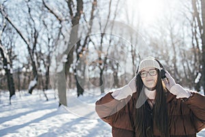 Young woman listening music on headphones on winter day