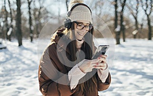 Young woman listening music on headphones on winter day