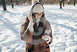 Young woman listening music with headphones on winter day