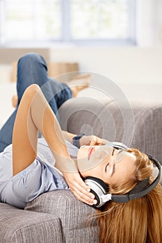 Young woman listening music laying on sofa