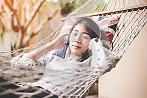 Young woman listening music relax lying in a hammock in the holiday