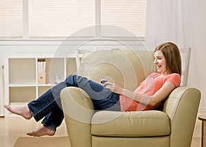 Young woman listening to mp3 player on armchair