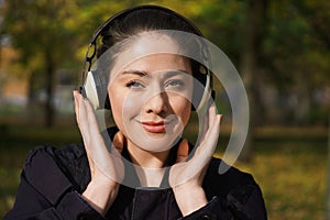 Young woman listening to music with cordless headphones outside