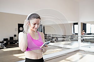 Young woman listening to music with earphones on smart phone app for fitness motivation. Athlete runner in sportswear