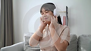 Young woman listening to music with headphone and relaxing while sitting on the sofa at home
