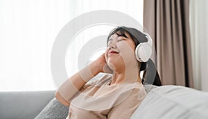 Young woman listening to music with headphone and relaxing while sitting on the sofa at home