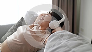 Young woman listening to music with headphone and relaxing while sitting on the sofa at home