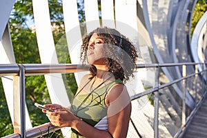 young woman listening to music with headphones while holding a smartphone