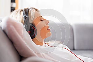 Young woman listening to music on headphones at home