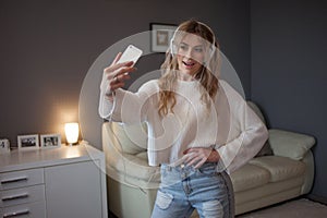 Young woman listening to music and take selfie, indoors