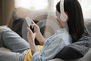 Young woman listening to music using smartphone at home.