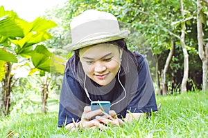 Young woman listening to music from your smart phone on the grass