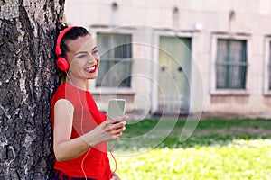 Young woman listens to music via headphones and smartphone