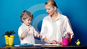 Young woman with a little boy painted with colored pencils and emotionally communicate on a blue background. Mom and son