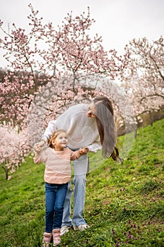 Young woman with little daughter in a blooming pink and white garden Petrin in Prague, spring time in Europe
