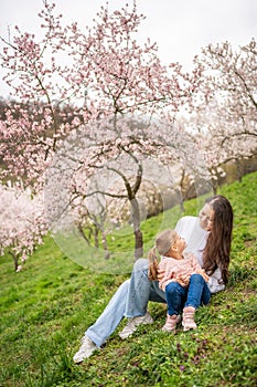 Young woman with little daughter in a blooming pink and white garden Petrin in Prague, spring time in Europe