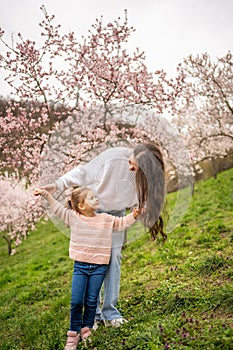 Young woman with little daughter in a blooming pink and white garden Petrin in Prague, spring time in Europe