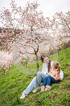 Young woman with little daughter in a blooming pink and white garden Petrin in Prague, spring time in Europe
