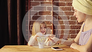 A young woman and a little girl eat yogurt at Breakfast.