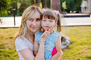 A young woman and a little girl are sitting on a bench in the park.Similarity and kinship