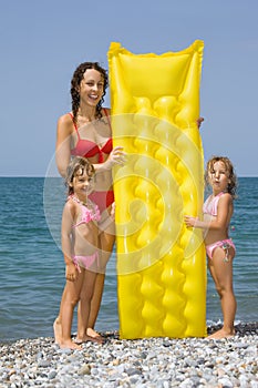 Young woman and little girls standing on beach