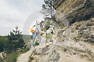 young woman with little toddler boy climbing by rocks