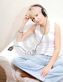 Woman in living room listening to MP3 player smiling