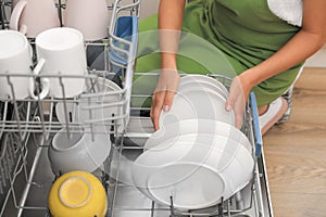 Young woman loading dishwasher in kitchen, closeup