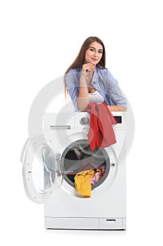 Young woman loading washing machine with dirty laundry