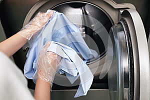 Young woman loading washing machine in dry-cleaning
